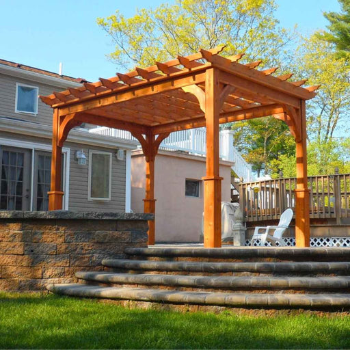 Freestanding Cedar Cozy Retreat pergola on a raised patio with curved stone steps and decorative corner braces.